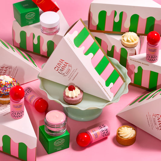 A collection of skincare products from OLIVIAUMMA, including a multivitamin serum and a pudding calming cream, presented in whimsical cake packaging.