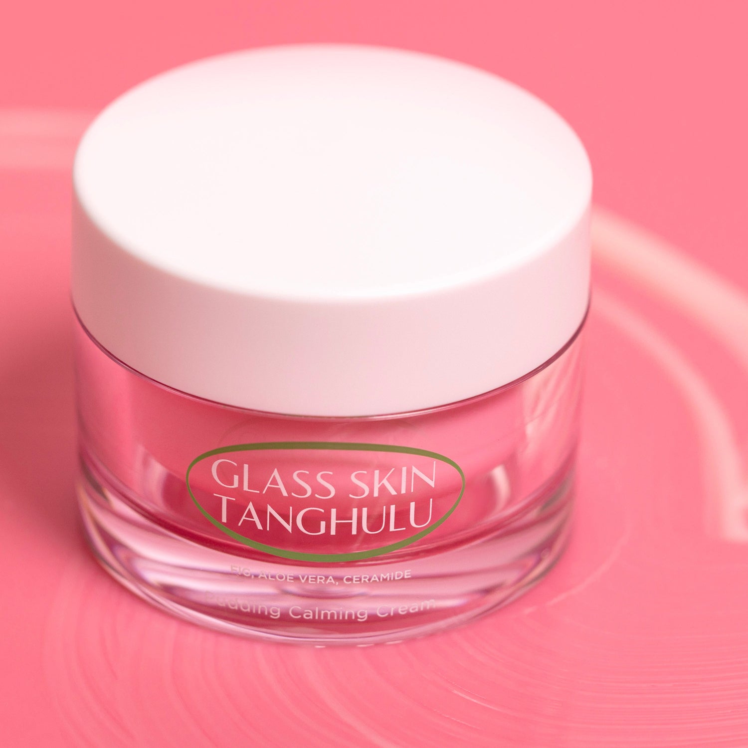 Glass skin cream jar with white lid on a pink background