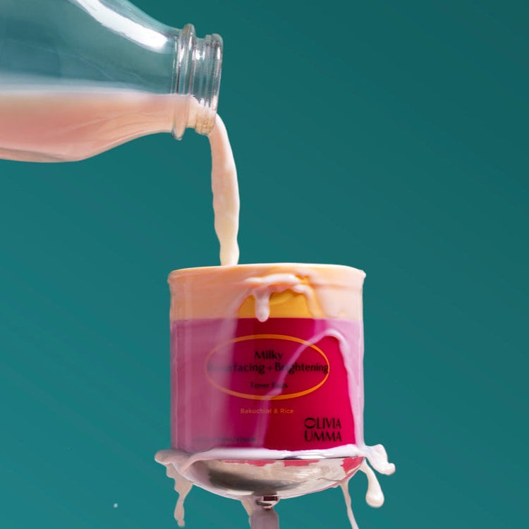 Bottle pouring milk into a pink container with a blue background, Milky Resurfacing + Brightening Toner Pads