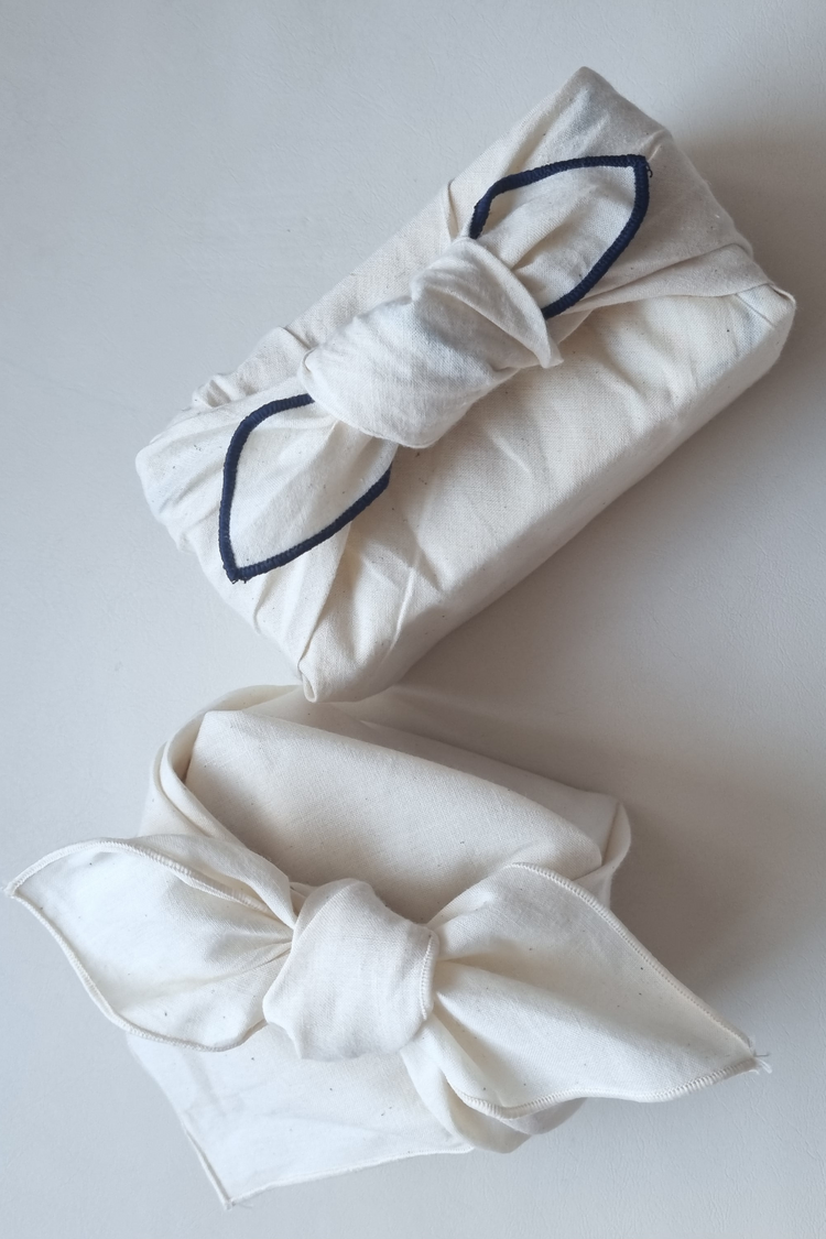 Two white Bojaki with navy blue elastic bands on a light gray background