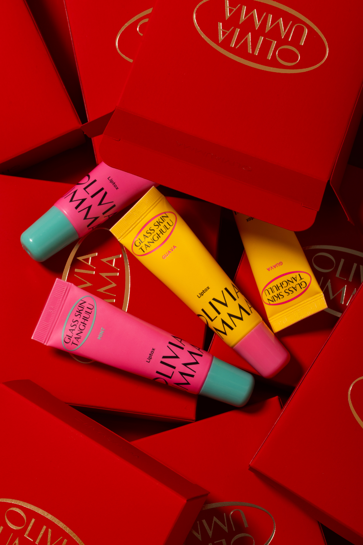 Colorful lip glosses in front of a red Olivia umma box