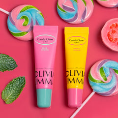 Two lip balms from Candy Glow on a pink background with colorful lollipops and mint leaves.