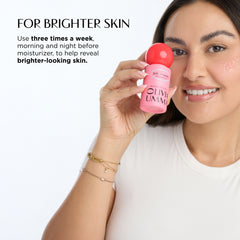 Woman holding a pink serum product with text about usage on a white background
