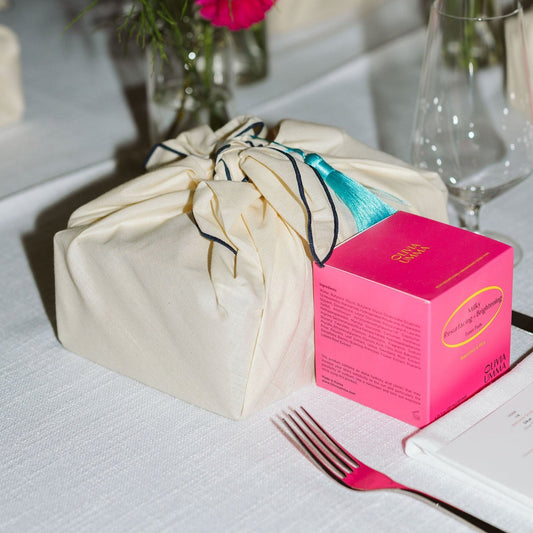Table setting with a Milky Resurfacing + Brightening Toner Pads, white Bojaki, and flowers on a tablecloth.