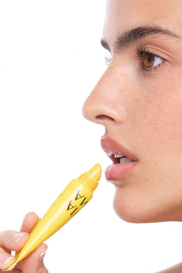 Person holding a lip tox guava product close to their lips on a white background