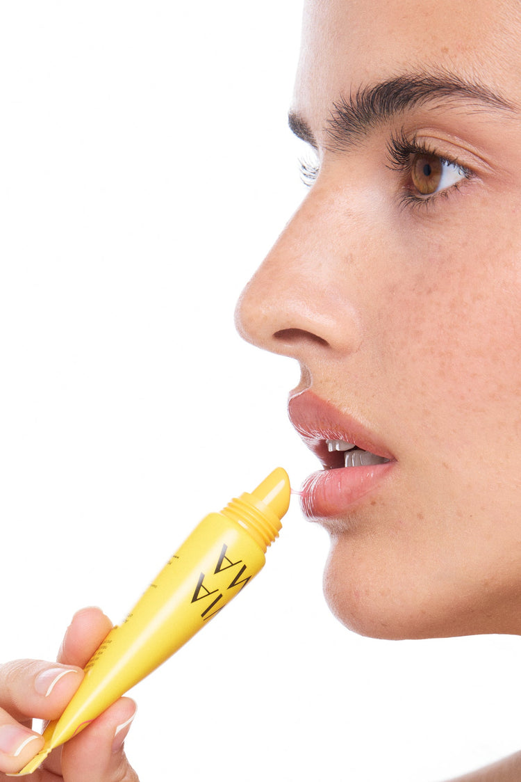 Person holding a lip tox guava product close to their lips on a white background